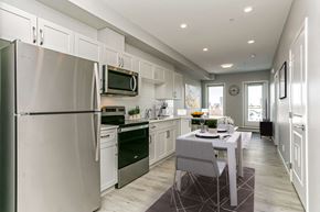 Edmonton apartment for rent - a white kitchen with stainless steel appliances and a dining table