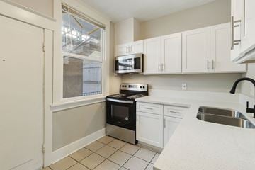 Tacoma apartment for rent - a kitchen with white cabinets and black appliances and a window