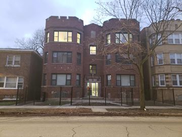 Chicago apartment for rent - A large red brick building with a black fence in front.