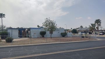 Phoenix apartment for rent - A street view with a white building and a fence.