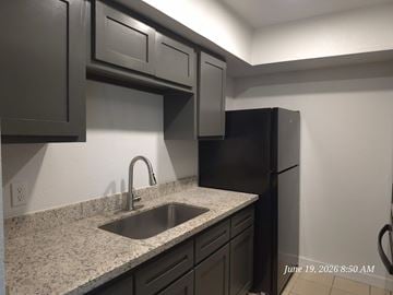 Laredo apartment for rent - A kitchen with black cabinets and a granite countertop.