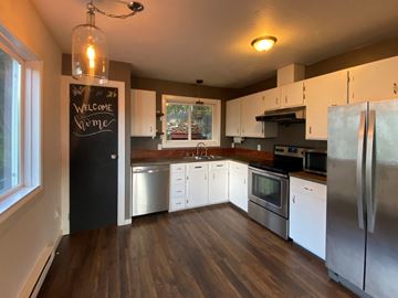 Sitka house for rent - A kitchen with a black fridge and a chalkboard that says "Welcome Home".
