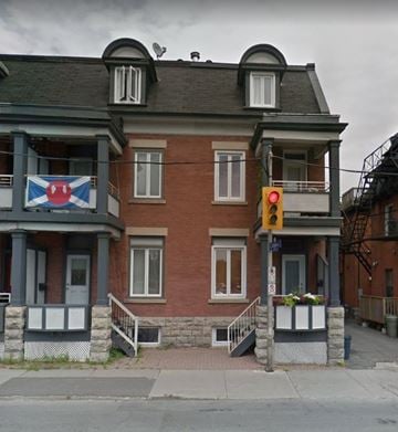 Ottawa apartment for rent - A red and white flag hangs on a balcony of a brick building.