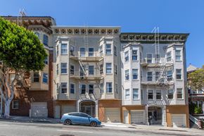 San Francisco apartment for rent - A blue car is parked in front of a building with a tree on the left.