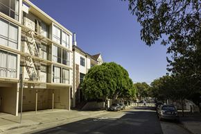 San Francisco apartment for rent - A street view of a residential area with apartment buildings and parked cars.