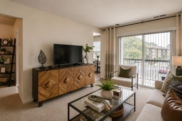 Glen Burnie apartment for rent - A living room with a glass coffee table and a wooden cabinet.
