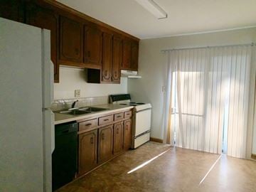 Kernersville apartment for rent - A kitchen with brown cabinets and a white refrigerator.