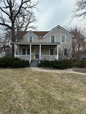 Grayslake apartment for rent - A house with a porch and a tree in front.
