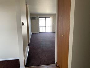 Grayslake apartment for rent - A hallway with a brown carpet and a wooden door.