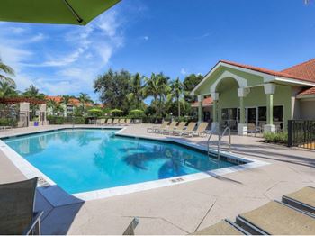 A swimming pool with chairs around it in front of a building