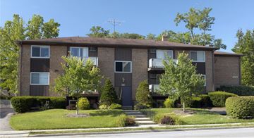 Cincinnati apartment for rent - A brown building with a green lawn in front.