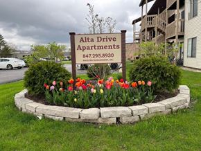 Grayslake apartment for rent - A sign for Alta Drive Apartments is surrounded by a flower bed.