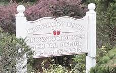 Middletown apartment for rent - a white sign in front of some bushes and trees