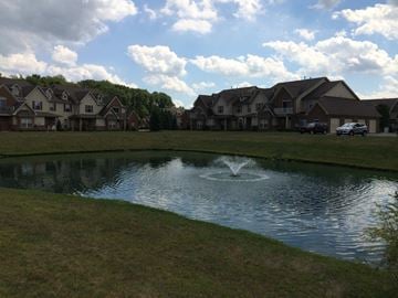 Sheffield Village apartment for rent - A pond in front of a row of houses with a fountain in the middle.