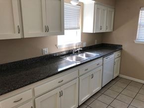 Bay City house for rent - A kitchen with white cabinets and a black countertop.