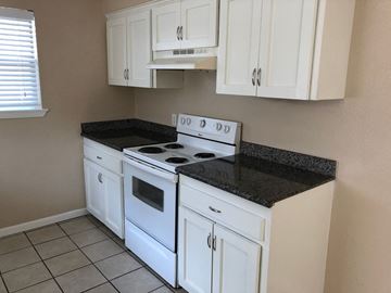 Bay City house for rent - A kitchen with white cabinets and a black countertop.