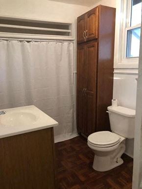 Morrow apartment for rent - A white toilet sits in a bathroom next to a sink and a wooden cabinet.