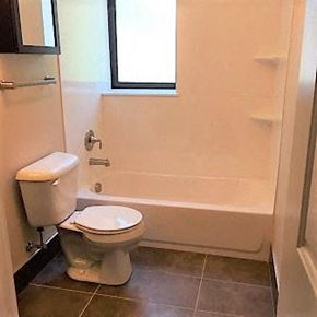 Saint Louis apartment for rent - A white toilet sits next to a bathtub in a bathroom.