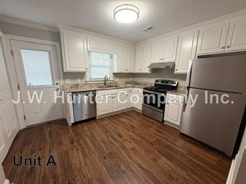 Wilson apartment for rent - A kitchen with wooden floors and white cabinets.