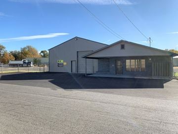 Yakima apartment for rent - A large industrial building with a grey roof and a white wall with a yellow sign on it.