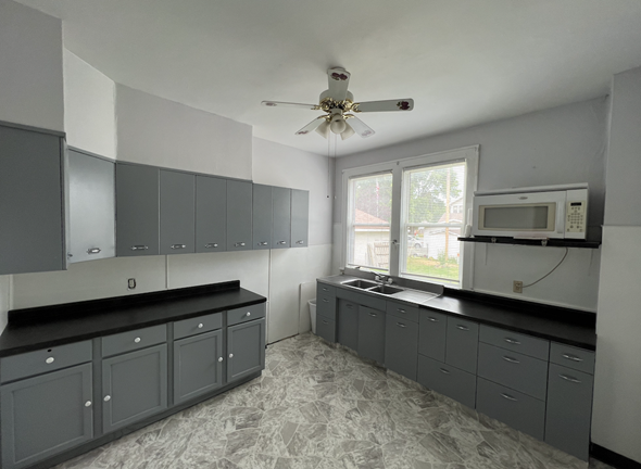 Fremont apartment for rent - an empty kitchen with gray cabinets and a ceiling fan