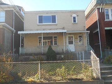 Pittsburgh apartment for rent - a yellow house with a fence in front of it