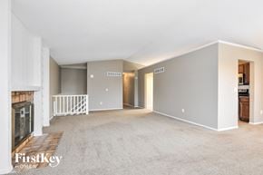 Lake Saint Louis house for rent - A spacious living room with a fireplace and a kitchen area in the background.