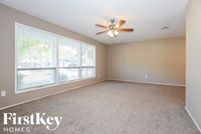 Florissant house for rent - A spacious room with a ceiling fan and large windows.