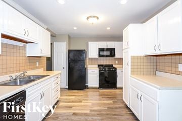 Florissant house for rent - A kitchen with white cabinets and a black fridge.