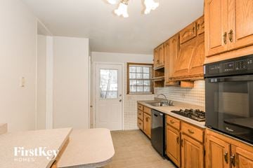 Florissant house for rent - a kitchen with wood cabinets and black appliances and a stove top oven