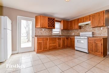 Florissant house for rent - a kitchen with wooden cabinets and white appliances