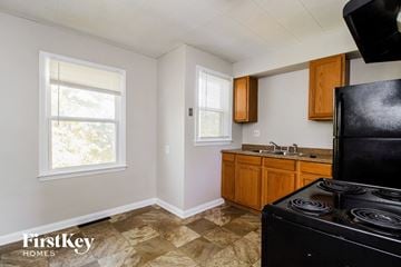 Cincinnati house for rent - A kitchen with a black stove top oven and wooden cabinets.