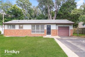 Florissant house for rent - A house with a red brick wall and a brown garage door is for sale.