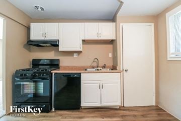 Florissant house for rent - A kitchen with a black stove top oven and a black dishwasher.