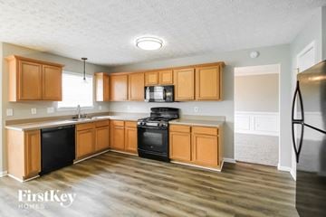 Covington house for rent - A kitchen with wooden cabinets and a black fridge.