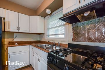 Saint Louis house for rent - a kitchen with white cabinets and a stove and sink
