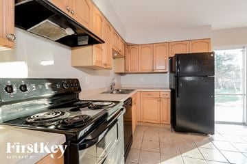 O'fallon house for rent - A kitchen with a black refrigerator and a stove with a glass top.