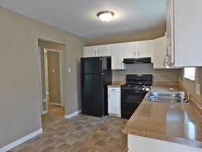 Florissant house for rent - a kitchen with black appliances and white cabinets