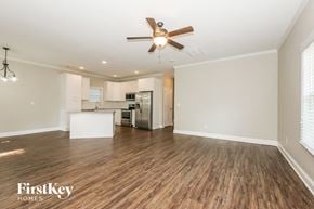 Newnan house for rent - an empty living room with a ceiling fan and a kitchen
