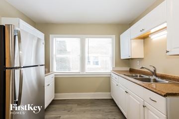 Waukegan house for rent - a kitchen with white cabinets and a sink and a refrigerator