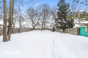 Waukegan house for rent - a backyard covered in snow with a green fence and trees