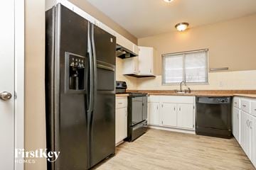 Saint Peters house for rent - A black refrigerator is in a kitchen with wooden floors and white cabinets.