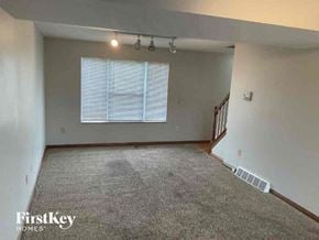 Covington house for rent - A room with a carpeted floor, a window with blinds, and a staircase.