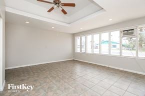 Tempe house for rent - A spacious room with a ceiling fan and large windows.