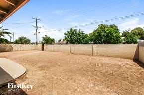 Tempe house for rent - A backyard with a fence and trees in the background.