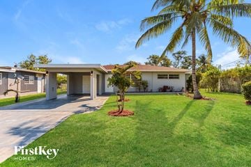 Plantation house for rent - a home with a palm tree in the yard and a driveway