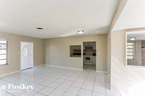 Plantation house for rent - an empty living room with a kitchen in the background