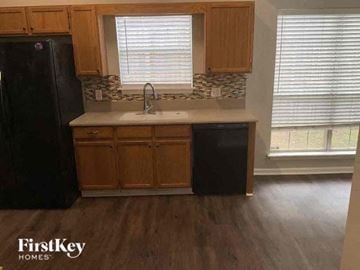 Covington house for rent - A kitchen with wooden cabinets and a black refrigerator.