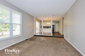 O'fallon house for rent - A spacious living room with a carpeted floor and a view of trees through the window.