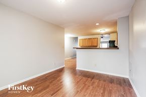 Brownsburg house for rent - A room with wooden floors and white walls, with a kitchen area visible in the background.